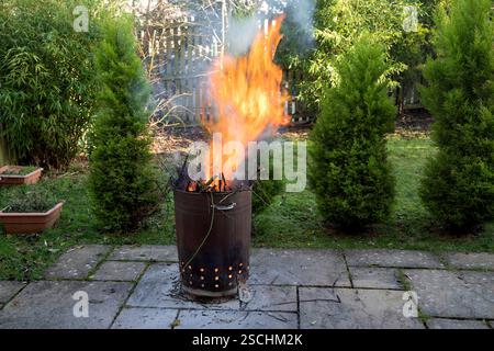 Brennende Gartenabfallverbrennungsanlage in einem städtischen Garten an einem Wintermorgen Stockfoto