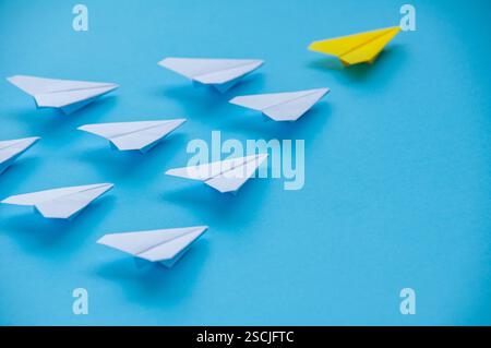 Nahansicht des gelben Papierflugzeugs Origami führende weiße Flugzeuge auf blauem Hintergrund mit anpassbarem Platz für Text. Wirtschaft und Führung SK Stockfoto