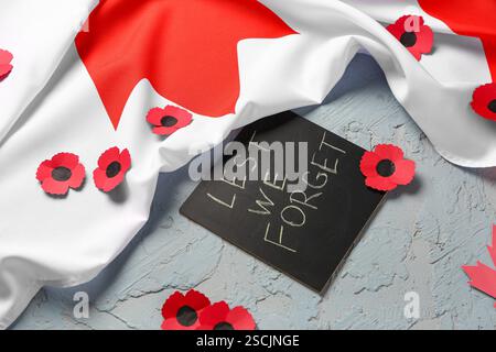 Mohnblumen mit kanadischer Flagge und Karte auf strukturiertem grauen Hintergrund. Gedenktag Stockfoto