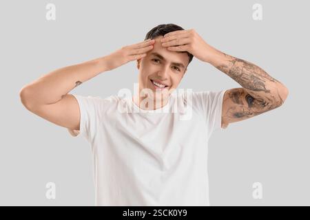 Junger Mann, der Gesichtsbauübung auf hellem Hintergrund macht Stockfoto