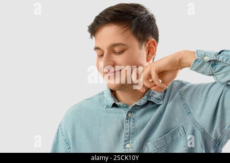 Junger Mann, der Gesichtsbauübung auf hellem Hintergrund macht Stockfoto
