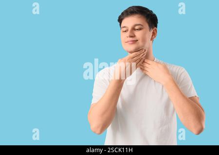 Junger Mann, der Gesichtsaufbauübung auf blauem Hintergrund macht Stockfoto