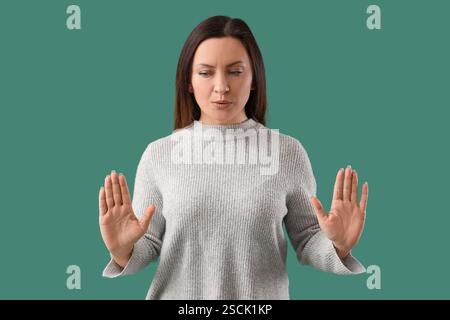 Besorgte Frau, die versucht, sich auf grünem Hintergrund zu beruhigen Stockfoto