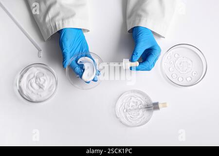Hände der Wissenschaftlerin, die Pipetten und Petrischalen mit Proben auf weißem Hintergrund halten Stockfoto