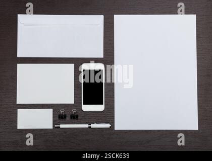 Sammlung von Schreibwaren auf einem Holztisch, einschließlich Smartphone und verschiedenen Papierformaten Stockfoto