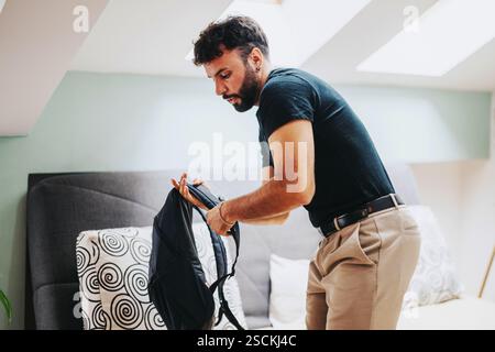 Junge Studentin, die einen Rucksack in einem modernen Schlafzimmer packt Stockfoto