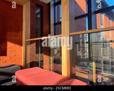 Modernes Wartezimmer mit roter Backsteinwand und großem Glasfenster Stockfoto