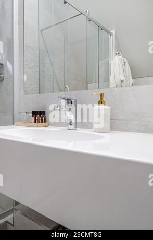Helles und elegantes Bad mit verglaster Dusche, wandmontierter Toilette und Fliesen in Marmoroptik für einen eleganten, luxuriösen Look. Stockfoto