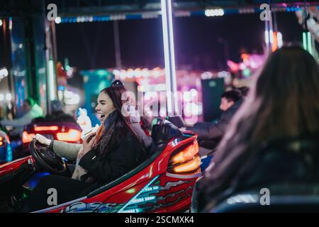 Freunde genießen Autoscooter bei einem lebhaften Winterkarneval bei Nacht Stockfoto