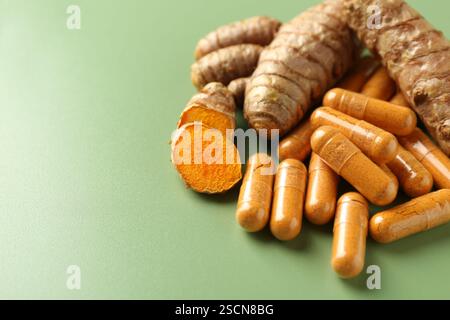 Kurkuma-Rhizome und -Kapseln auf grünem Hintergrund, Nahaufnahme. Leerzeichen für Text Stockfoto