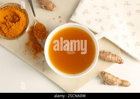 Aromatischer Kurkuma-Tee, Pulver und Rhizome auf weißem Tisch, flach gelegen Stockfoto