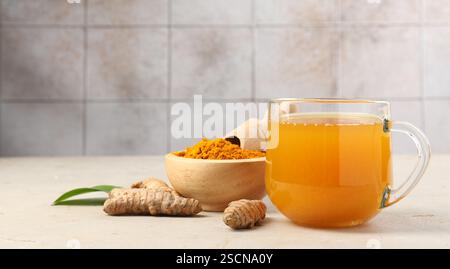 Aromatischer Kurkuma-Tee, Rhizome und Pulver auf weißem, strukturiertem Tisch. Leerzeichen für Text Stockfoto