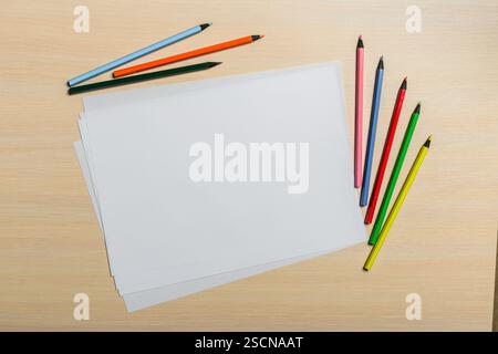 Bunte Bleistifte und leere Blätter warten auf künstlerische Kreationen auf einem Holztisch Stockfoto