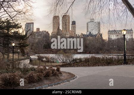Der gewundene Pfad im Central Park neben dem gefrorenen See spiegelt die ruhige Winterlandschaft von New York City im Nachmittagslicht wider. Stockfoto