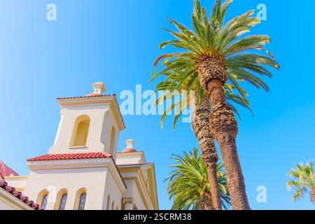 Blick auf Palmen neben einem architektonischen Gebäude, das Riverside im Mission-Revival-Stil vor einem blauen Himmel zeigt. Stockfoto
