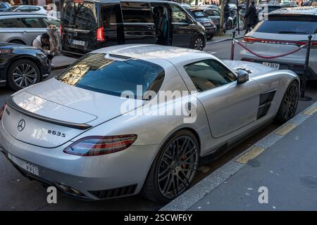 Eleganter silberner Sportwagen, der in der Nähe von Luxusfahrzeugen in urbaner Umgebung geparkt wird Stockfoto