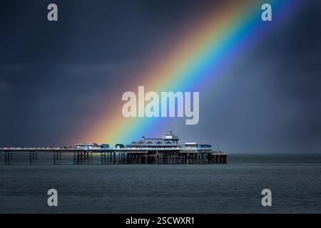 Intensiver Regenbogen und stimmungsvoller Himmel über dem Llandudno Pier, Llandudno, Nordwales, Großbritannien Stockfoto