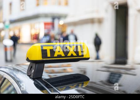 Urbane Straßenszene mit einem Taxischild im Fokus und verschwommenen Fußgängern im Stadtzentrum Stockfoto