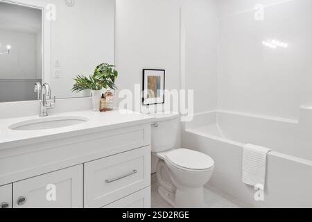 Badezimmer mit weißer Toilette, Waschbecken und Badewanne. Die Badewanne ist weiß und hat ein Handtuch drauf Stockfoto