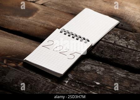 2025 geschrieben in einem Notizbuch, das auf einem alten hölzernen Brett liegt Stockfoto