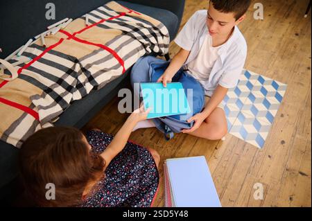 Zwei Kinder teilen ihre Notebooks und fördern so die Zusammenarbeit und das Lernen in einer gemütlichen Umgebung. Ermutigt zur Zusammenarbeit und betont den Wert Stockfoto