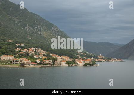 Bucht von Kotor, Montenegro - 2. Juli 2024: Dorf Prcanj. Küste von Süden aus gesehen mit historischen und neu gebauten Häusern. Kirche der Geburt von Stockfoto