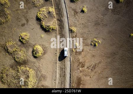 Ein Drohnenfoto, das ein weißes Fahrzeug zeigt, das auf einer schmalen Feldstraße in der Nähe von Landmannalaugar fährt, die Rainbow Mountains in Island genannt werden. E Stockfoto