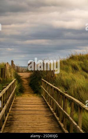 Eine hölzerne Fußgängerbrücke führt zum Strand Stockfoto