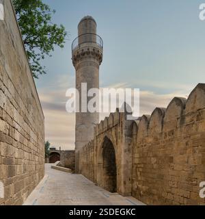Das Minarett der Schah-Moschee erhebt sich vor Sonnenuntergang über den umliegenden Gebäuden in Baku, Aserbaidschan. Die Moschee ist mit dem Palast der Shirvanshahs verbunden und ist ein bemerkenswertes Wahrzeichen der Stadt Stockfoto