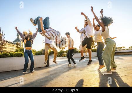 Mann mit lockigen Haaren, der während des Sonnenuntergangs Spaß mit Freunden in der Stadt macht Stockfoto