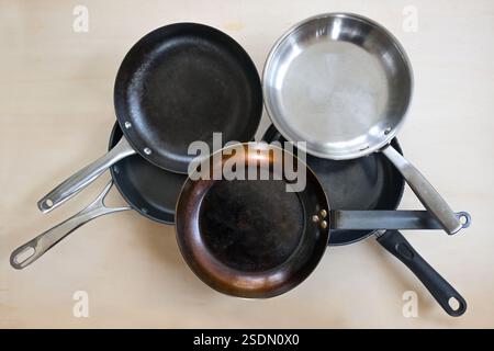 Auswahl an Bratpfannen aus verschiedenen Materialien, Edelstahl, Gusseisen, Karbonstahl und PTFE Antihaftbeschichtet, hoher Winkel von oben, l Stockfoto