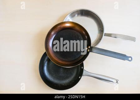 Drei Pfannen aus Naturmaterial für gesundes Kochen aus Kohlenstoffstahl, Edelstahl und Gusseisen ohne ungesunde Antihaftbeschichtung, c Stockfoto