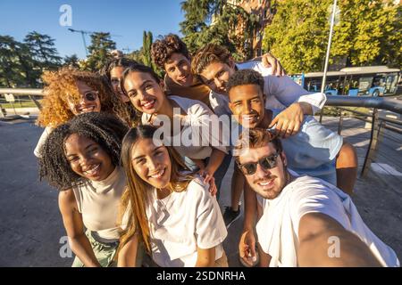 Multirassische Gruppe glücklicher junger Freunde, die bei Sonnenuntergang auf der Straße Selfie machen Stockfoto