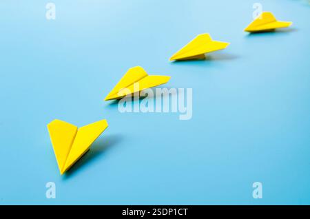 Nahansicht des gelben Papierflugzeugs Origami führende weiße Flugzeuge auf blauem Hintergrund mit anpassbarem Platz für Text. Wirtschaft und Führung SK Stockfoto