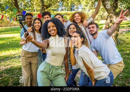 Multiethnische Freunde machen Selfie mit tragbarer Kamera und Stativ zusammen in einem Park Stockfoto