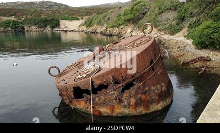 Rostiger zylindrischer Metallbehälter, der am Steinstrand steht. Stockfoto