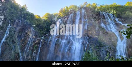 Ein majestätischer Wasserfall stürzt über eine felsige Klippe, umgeben von üppigem Grün im Nationalpark Plitvicer Seen, Kroatien. Stockfoto