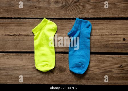 Zwei kurze Damensocken, eine gelbe, eine blaue, liegen zu Hause auf dem Boden, modische Socken Stockfoto