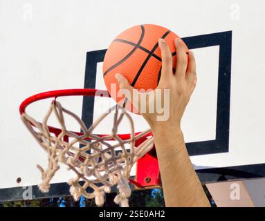 Abgeschnitten von der Hand eines männlichen Basketballspielers in Aktion gegen draußen Stockfoto