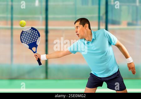 Porträt eines jungen männlichen Paddeltennisspielers, der in Sportanlagen steht und den Ball schwatzt Stockfoto
