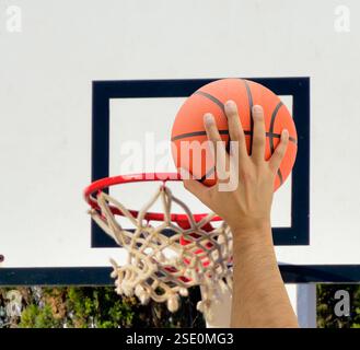 Abgeschnitten von der Hand eines männlichen Basketballspielers in Aktion gegen draußen Stockfoto