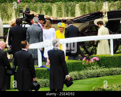 Königin Elizabeth II. Trägt einen gelben Mantel und einen gelben Hut, mit einem frechen Lächeln auf Royal Ascot. Mit Prinz Charles und Prinzessin Royal. Stockfoto