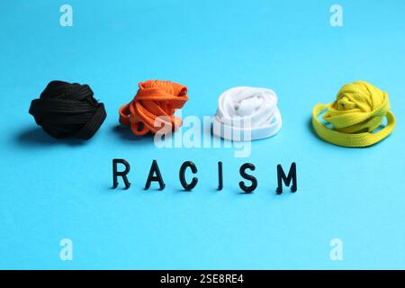 Wort Rassismus und Schnürsenkel in verschiedenen Farben auf hellblauem Hintergrund Stockfoto