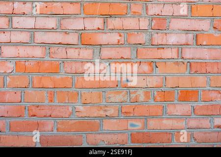 Eine strukturierte Wand aus roten Ziegeln zeigt verschiedene Farbtöne und Mängel. Diese robuste Oberfläche spiegelt den für cl typischen Charme und Charakter alter Zeiten wider Stockfoto