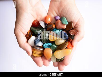 Eine junge Frau, die eine Sammlung verschiedener roher und glänzender Edelsteine in ihrer Hand hält, die ihre natürliche Schönheit und einzigartige Texturen zeigen Stockfoto