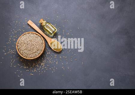 Glas Flasche von Kümmel ätherisches Öl mit Kümmel Pulver in Holzlöffel auf rustikalem Tisch ( Cuminum cyminum ) Stockfoto