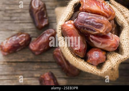 Datteln, leckere Trockenfrüchte in Sackleinen oder Schüssel auf rustikalem Holzhintergrund, ramadan Kareem Essen, Kopierraum selektiver Fokus (Phoenix dactylifera ) Stockfoto