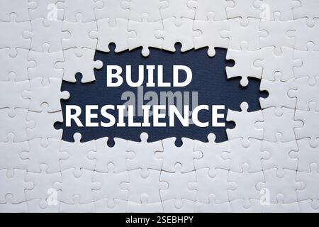 Symbol für Belastbarkeit erstellen. Weißes Puzzle mit Wörtern schafft Widerstandsfähigkeit. Wunderschöner dunkelblauer Hintergrund. Business- und Build Resilience-Konzept. Kopierbereich. Stockfoto