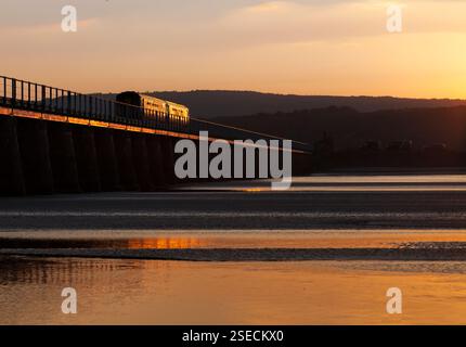 Der Supersprinterzug der Nordbahn der Klasse 156 überquert den Arnside Viadukt auf der landschaftlich reizvollen Cumbrian Coast Railway, die in der untergehenden Sonne glitzert Stockfoto