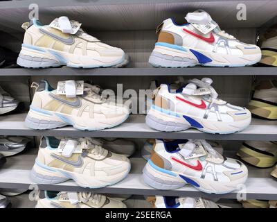 Stilvolle weiße Sneakers mit bunten Akzenten auf den Regalen im Schuhgeschäft. Stockfoto